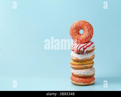 Stack of assorted donuts on blue background. Many colorful glazed doughnut with sprinkles stacked with copy space Stock Photo