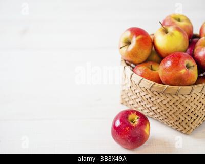 Apples harvest concept. Braided bamboo basket with red apples on white wooden background with copy space for text or design Stock Photo