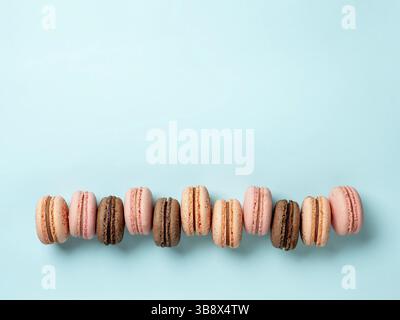 Macarons with copy space. Row of perfect french macarons or macaroons on blue background. Top view or flat lay Stock Photo