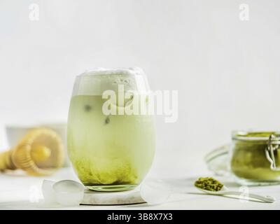 Iced Matcha Latte Tea with whipped cream in tumbler glass and ingredients on white marble background. Copy space for txt or design Stock Photo
