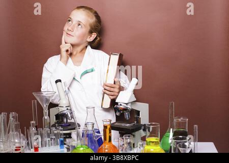Thoughtful schoolgirl standing near blackboard in the laboratory classes in chemistry Stock Photo
