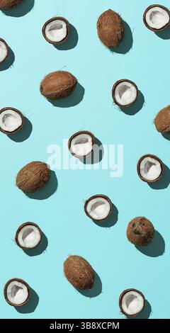 Creative layout of coconuts half on blue background. Tropical pattern, top view or flat lay. Hard light pop art minimal summer background. Vertical ba Stock Photo