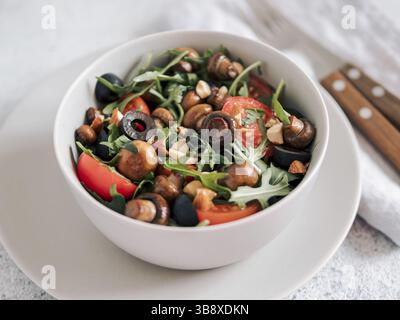 Salad with arugula, mini champignons, cherry tomatoes, black olives, pine nuts. Vegetarian salad ready-to-eat. Horizontal Stock Photo