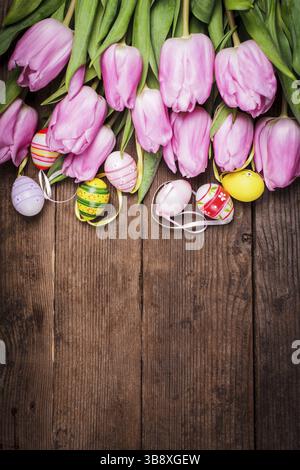 Tulips and eggs border over wooden backdrop. Easter decorations Stock Photo