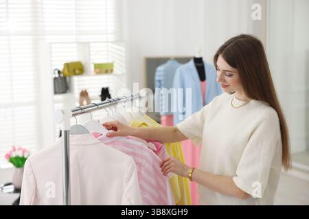Fashion stylist choosing clothes from rack in studio Stock Photo