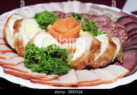 Plate with collation close up on table. Peaces of various sausage and flower from carrot. Shallow DOF Stock Photo
