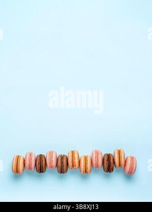 Macarons with copy space. Row of perfect french macarons or macaroons on blue background. Top view or flat lay Stock Photo