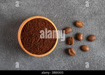Coffee beans with a bowl of ground coffee on black background Stock Photo