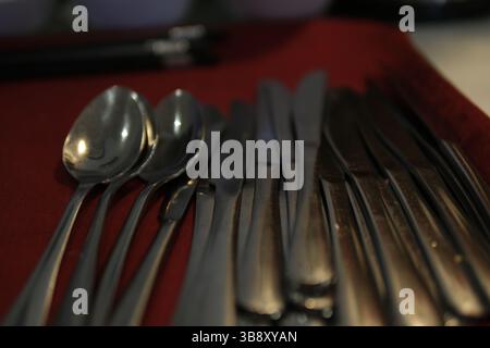 A rustic flatware set consisting of a spoon, fork, and knife arranged on a grey cloth napkin, evoking vintage charm and functionality. High quality photo Stock Photo