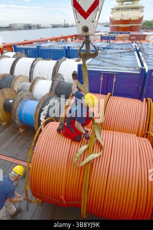 Crane unloads rolls of PVC cable sheathing from cargo ship. Crane is ...