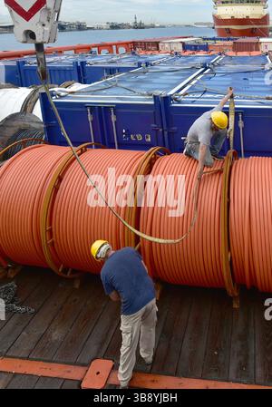 Crane unloads rolls of PVC cable sheathing from cargo ship. Crane is ...