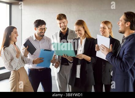 Business partners having work meeting, discussing marketing strategies, holds papers and laptop Stock Photo