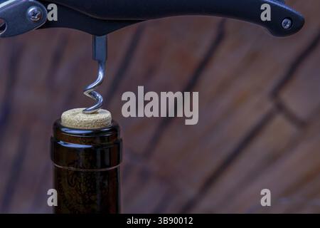 Wine bottle being opened by a waiter using a corkscrew, ready to be served to customers Stock Photo