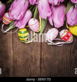 Tulips and eggs border over wooden backdrop. Easter decorations Stock Photo