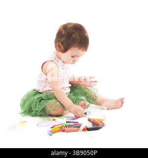 Toddler girl draws with wax crayons on the paper Stock Photo
