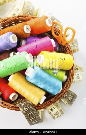Sewing items in basket: threads, pins, meter and scissors on white Stock Photo