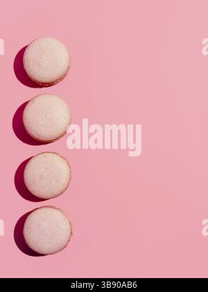 Pink macarons with copy space. Row of perfect french macarons or macaroons on pink background. Top view or flat lay. Hard light Stock Photo