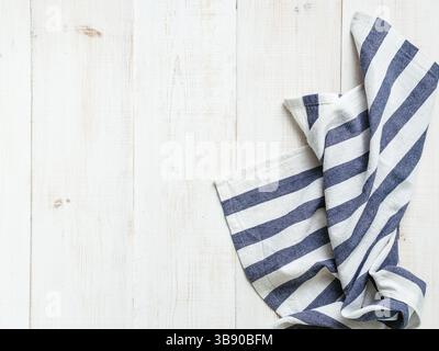 View from above on white wooden table with linen kitchen towel or textile napkin. Blue tablecloth on white wood tabletop. Copy space for text. Can use Stock Photo