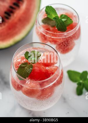 Watermelon ice with sparkling water or soda in glass tumbler. Summer party idea and recipe, add color and flavor for soda or other drink. Vertical Stock Photo