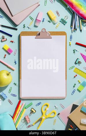 Clipboard with empty white sheet and school stationery. Back to school concept with copy space over blue background. Vertical. Trendy clipboard mockup Stock Photo