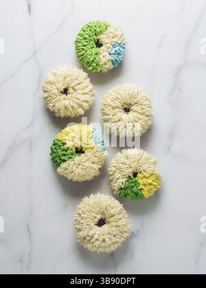 Shag donuts on white marble background. Unusual trendy colorful donuts with vanilla buttercream. Copy space. Top view or flat lay. Vertical Stock Photo