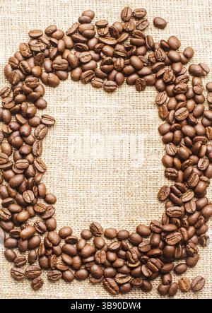 Spilled coffee beans frame over burlap textile Stock Photo