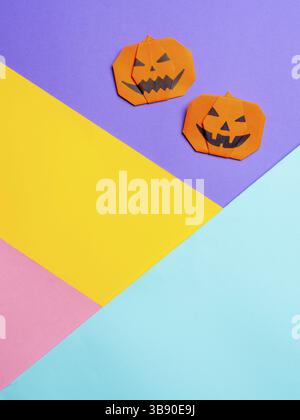 Halloween concept. Paper origami pumpkin on colorful background. Simple idea for halloween - easy made paper pumpkins on multicolor blue, yellow, pink Stock Photo