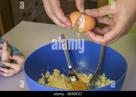 Hand pours out raw egg of the shell in shortbread dough Stock Photo