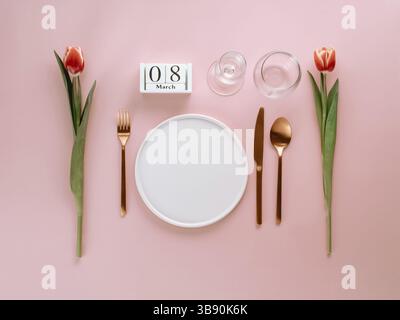 8 march table setting. Empty white plate, calendar with march eight date and red tulip on pink background. Aesthetic stylish dinner table setting for Stock Photo