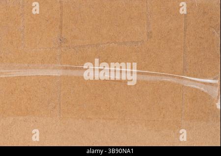 Cardboard surface features clear tape used to secure packaging, indicating preparation for shipping. Stock Photo
