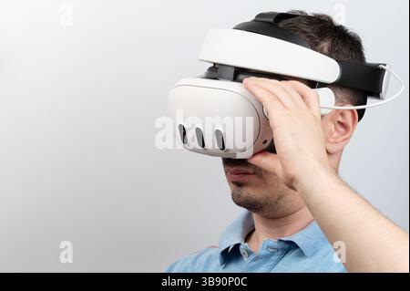 Man engages with virtual reality headset, exploring immersive digital environments in bright, indoor space. Stock Photo
