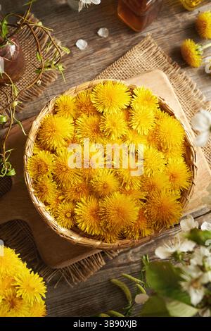 Dandelion flowers in a wicker basket on a table, top view Stock Photo