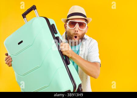 Tourist with suitcase going on summer holiday and looking at camera with funny surprised face Stock Photo
