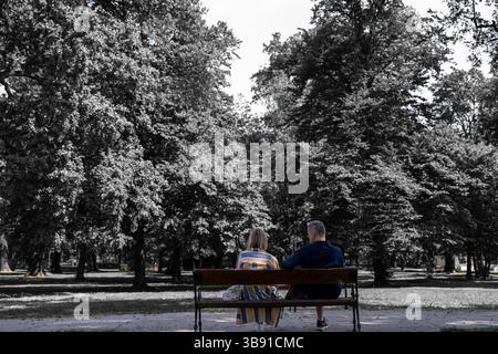 young couple sitting on bench, family in park, black and white Stock Photo