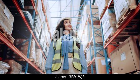 Warehouse, walking and woman in logistics inventory for checking boxes, shelf and stock management in distribution. Low angle, smile and plant worker Stock Photo