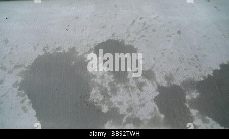 Wet cement stains are creating abstract patterns on a concrete surface, adding an industrial aesthetic Stock Photo
