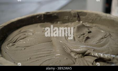 Close-up of cement plaster being mixed in a bucket, ready for application in construction or renovation work Stock Photo