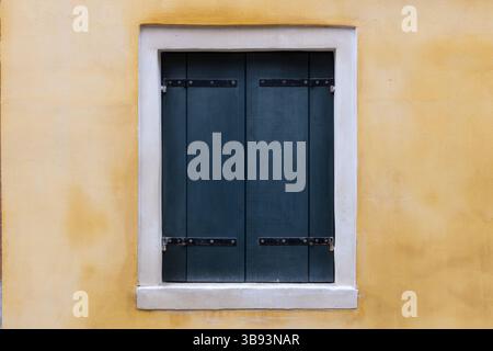 Closed Dark Shutters on Yellow Wall Stock Photo