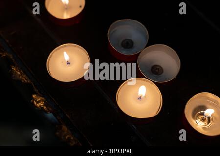 Burning Tealight Candles in Dark Interior Stock Photo