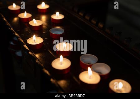 Multiple Tealight Candles Burning in Darkness Stock Photo