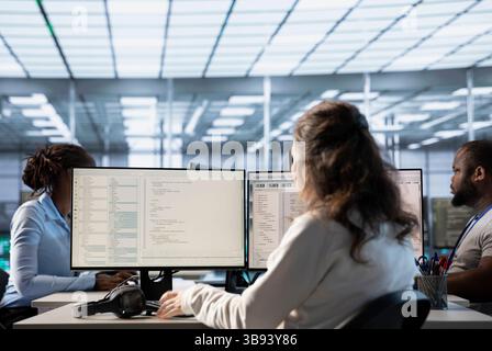 Engineer typing on computer in server hub, checking recovery plan, monitoring data center energy consumption, solving tasks. Technician inspecting rackmounts in data center Stock Photo