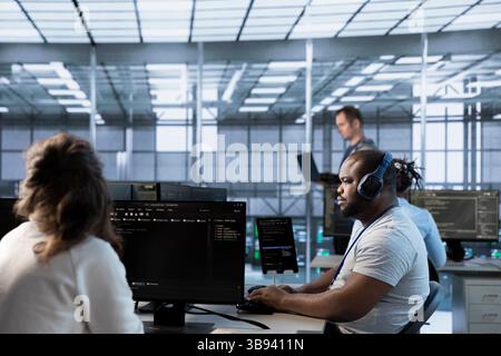 African american man in data center coordinating deployment of server architecture, improving data processing speed. Worker listening music in server farm, configuring and testing equipment Stock Photo