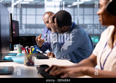 Technician doing face palm gesture, failing to optimize server farm for data processing requirements of customers. Upset man in data center struggling to make equipment operate efficiently Stock Photo