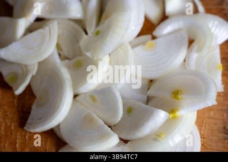 White onions are neatly sliced into thin rounds and arranged on a wooden cutting board, showcasing their glossy texture and fresh appearance. Perfect Stock Photo