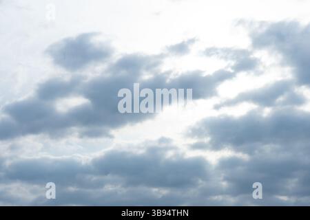 A cloudy sky dominates the view, with thick gray clouds creating a muted light. The sun peeks through, casting a soft glow over the landscape below, t Stock Photo