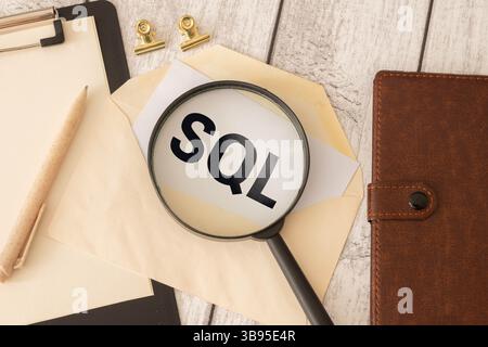 SQL programming language. word sql and laptop, glasses and coffee on wooden table Stock Photo