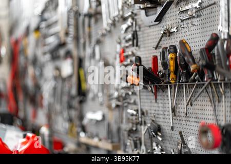 Various hand tools organized on pegboard in workshop. Screwdrivers, wrenches, and pliers neatly arranged for easy access, creating a functional workspace in garage Stock Photo