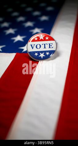 Vote button pin, in the red white and blue of the United States America on the American flag. To encourage voting, national pride, and political invol Stock Photo