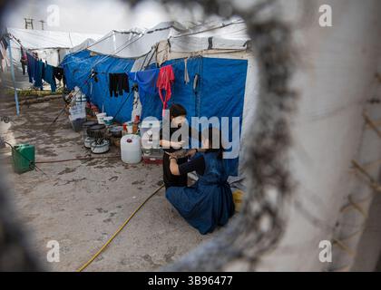 February 26, 2022, Syria: An Asian woman dresses her son near their tent. Several dozen nationalities are represented among the detainees at the Roj camp. France would have nearly 250 children and 80 adult nationals there.  (Credit Image: © Sadak Souici/ZUMA Press Wire) Stock Photo