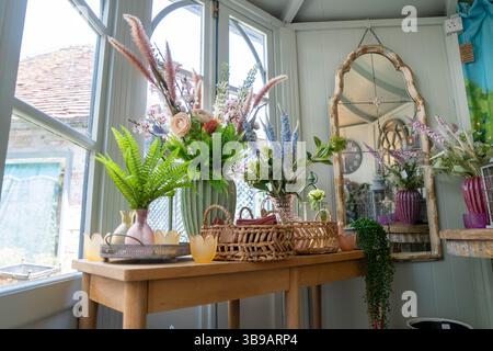 Artificial Flowers and fern leaves on a table in the window of Interior design shop in Amersham UK selling home wares. Stock Photo